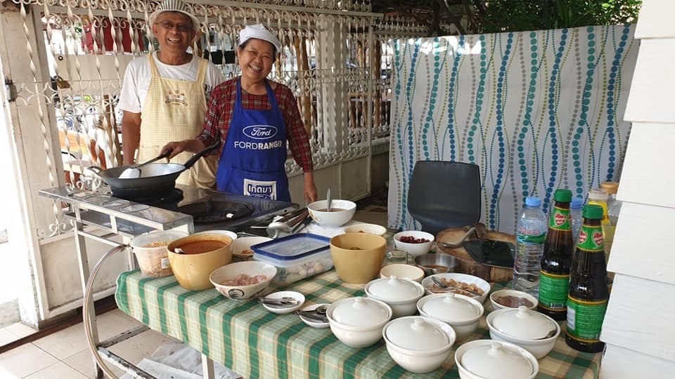 Two people cooking together at the outdoor stove.