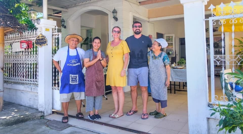 Guests and the family at the white gate of the house.